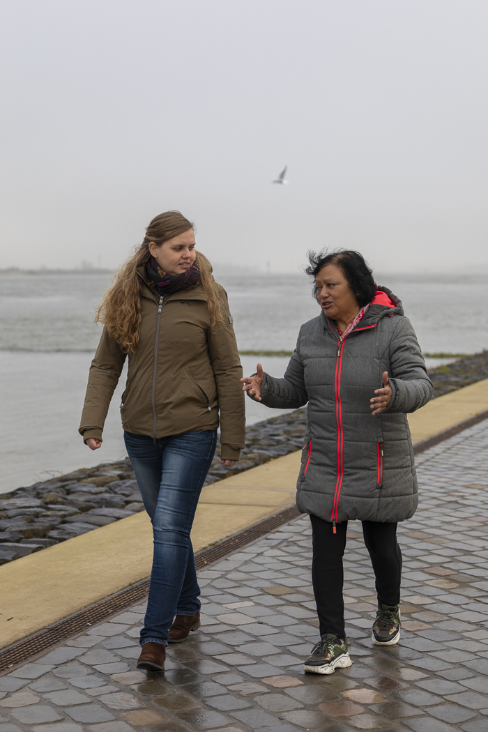 editorial foto bij interview van de twee verloskundigen die langs de rivier lopen en samen overleggen.